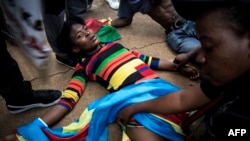FILE - A Congolese protester lies on the ground after police opened fire wth rubber bullets while they protested outside the Democratic Republic of the Congo's embassy in defiance of their president, Joseph Kabila, Dec. 20, 2016 in Pretoria, South Africa.