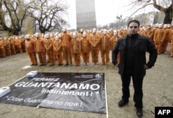 Amnesty International activists dressed in orange as the Guantanamo Bay prisonners, pose with French former prisonner, Mourad Benchellali, in front of a replica of the U.S. Statue of Liberty, in Paris, Jan. 6, 2007..