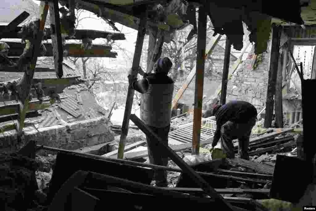 Local residents remove debris from a house damaged by recent shelling in Donetsk, Jan. 21, 2015.