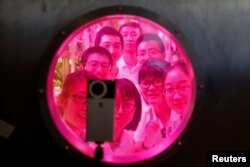 Volunteers smile to a camera from inside a simulated space cabin in which they temporarily live as a part of a scientistic Lunar Palace 365 Project, at Beihang University in Beijing, China, July 9, 2017.