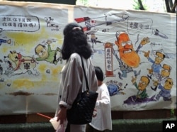 1996年3月23日，台北一个市场上的漫画。左侧漫画上有江泽民。右侧漫画上，台湾总统李登辉（右）安抚他的竞争对手说，他有18套办法对付中国导弹。