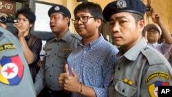 Reuters journalist Wa Lone, center, is escorted by police as he returns to court after a break during their trial, Feb. 1, 2018, outside of Yangon, Myanmar. 