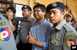 Reuters journalist Wa Lone, center, is escorted by police as he returns to court after a break during their trial, Feb. 1, 2018, outside of Yangon, Myanmar.