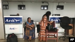 Stranded passengers stand at the closed Arik Air check-in counter following a protest over unpaid salaries by staff in Lagos, Nigeria, Tuesday, Dec. 20, 2016.