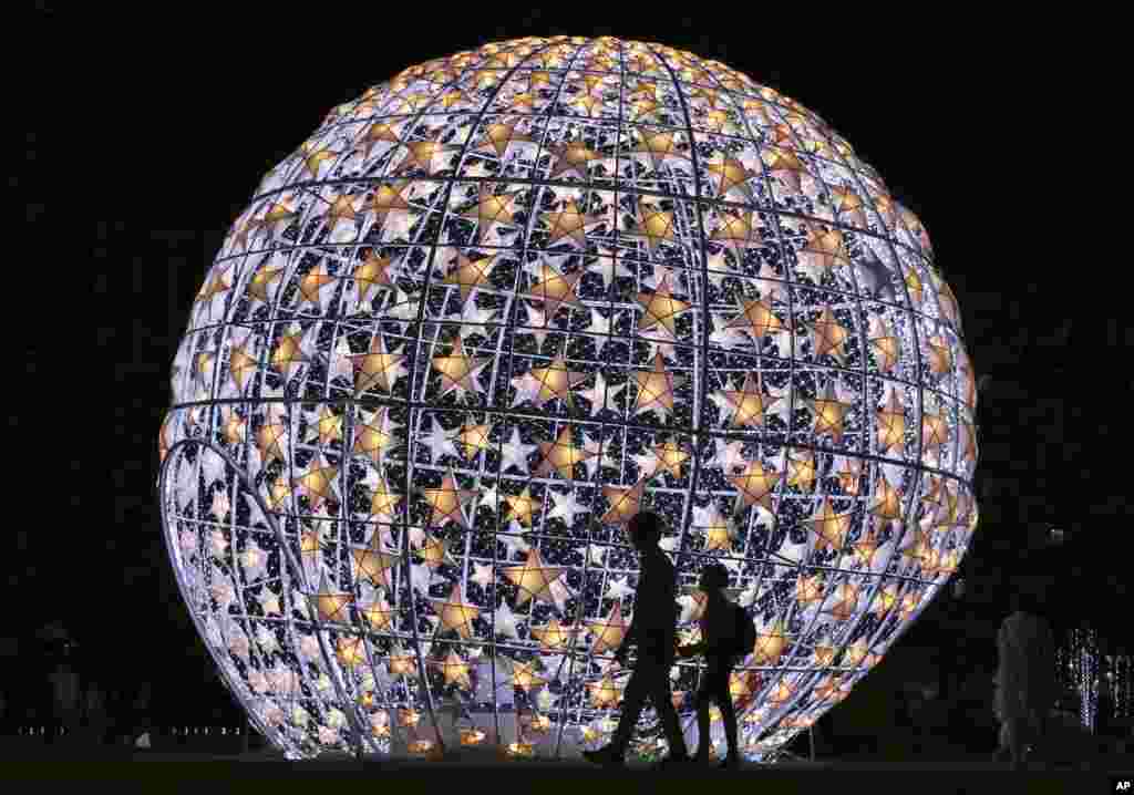 Locals walk past a lit Christmas display at a park in Pasay, south of Manila, Philippines.