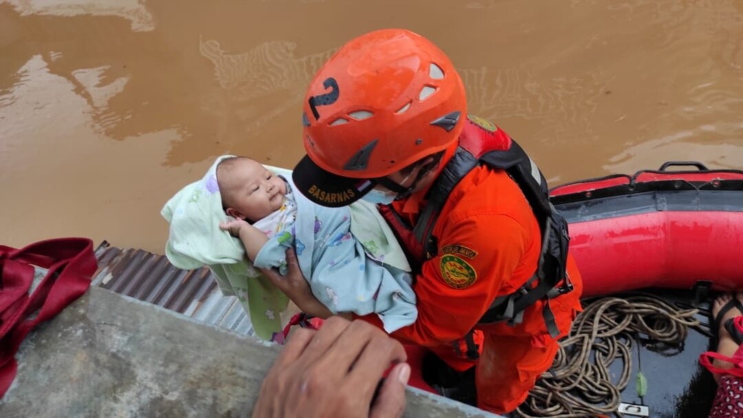 Personel Badan SAR Nasional (Basarnas) mengevakuasi bayi di daerah terdampak banjir di Jakarta, 20 Februari 2021. (Foto: Basarnas via REUTERS)