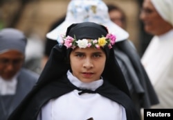 A young woman dressed as St. Rosa of Lima, patron saint of Peru, waits for Pope Francis to arrive at the nunciature, in Lima, Peru, Jan. 18, 2018.