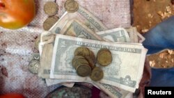 FILE - Cuban pesos are seen at at vegetable stall at a market in Sagua La Grande, Villaclara province in central Cuba.