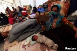 A displaced woman sits next to her sleeping child at a refugee camp in the Makhmour area near Mosul, Iraq, June 15, 2016.
