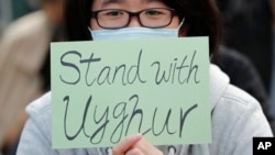 FILE - A man holds a sign during a rally to show support for Uyghurs and their fight for human rights, in Hong Kong, Dec. 22, 2019. Fifty journalists are imprisoned in China, according to a 2021 report released in December; 22 of those are Uyghur journalists from Xinjiang.