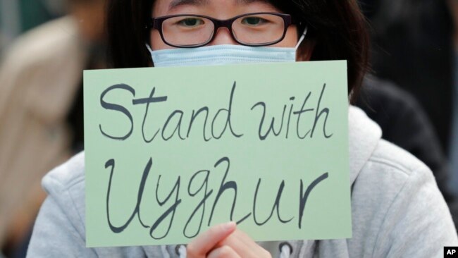 FILE - A man holds a sign during a rally to show support for Uyghurs and their fight for human rights, in Hong Kong, Dec. 22, 2019. Fifty journalists are imprisoned in China, according to a 2021 report released in December; 22 of those are Uyghur journalists from Xinjiang.