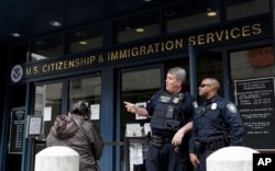 FILE - Two officers are seen outside the entrance to the Immigration and Customs Enforcement office in San Francisco, Feb. 28, 2018.