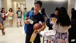 资料照片：一名中国留学生走进德州大学达拉斯分校为中国留学生举办的新生欢迎活动。（2015年8月22日）