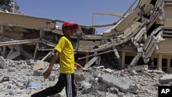 In this photo taken on a government-organized tour a child walks past the rubble of a university building in Zlitan, Libya, August 4, 2011