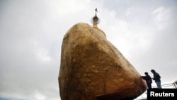 Buddhist devotees give offerings at the Kyaikhtiyo Pagoda, also known as the Golden Rock Pagoda, (File photo).