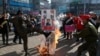 FILE - A member of a South Korean conservative group kicks a burning banner with an image of North Korean leader Kim Jong Un and North Korean flags during a rally denouncing the North, in Paju, South Korea, Jan. 11, 2016.