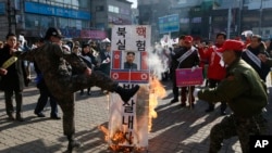 FILE - A member of a South Korean conservative group kicks a burning banner with an image of North Korean leader Kim Jong Un and North Korean flags during a rally denouncing the North, in Paju, South Korea, Jan. 11, 2016.