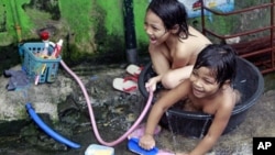 Informal settlers play while bathing on a tub in San Juan, Manila. The Philippines is expected to sustain post-crisis economic growth, but this will be without development which may increase poverty, according to a new study from the United Nations, May 2