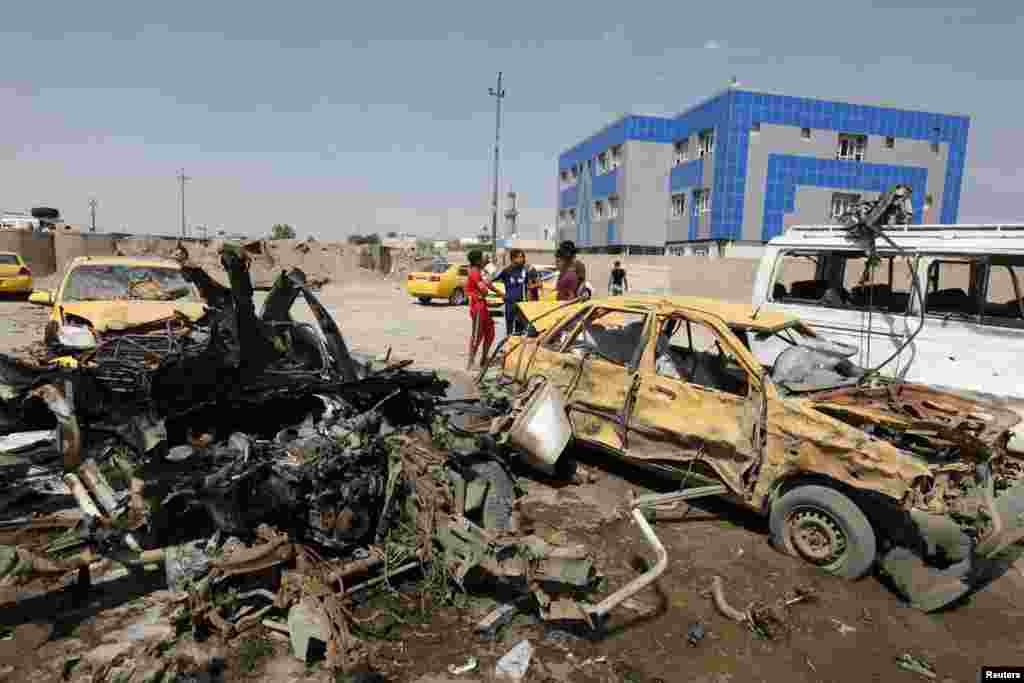 People gather at the site of car bomb attack in Baghdad, May 13, 2014. 