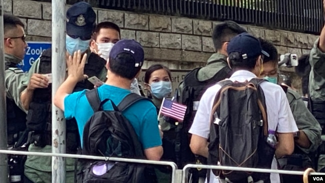 香港市民李先生手持小型的紙製美國國旗，與多名朋友7月4日下午到美國駐港總領事館附近慶祝美國國慶，他們被大批警員截查。(美國之音 湯惠芸拍攝)