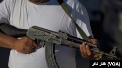 Seorang pria yang menjadi anggota dari kelompok pengamanan swakarsa di Meksiko tampak memegang senapan AK-47 ketika berjaga di Antunez, Michoacan, Meksiko, pada 11 Januari 2014. (Foto: AP/Eduardo Verdugo)
