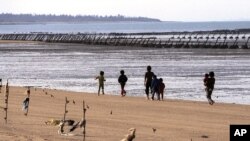 FILE - A family strolls the beaches with shores are lined with iron staves and the land's edge lined with mines, on Taiwan's Kinmen Island, 1.2 miles off China's south east coast, Dec. 13, 2001.