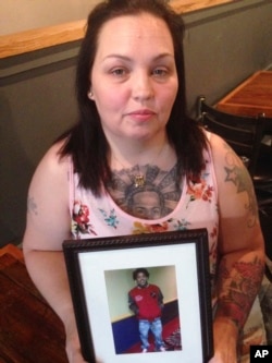 FILE - In this May 19, 2017, photo, Angela Williams holds a photo of her 18-year-old son, Cameron D. Pugh, who was killed as part of a murder spree that hit Louisville, Kentucky, in 2016. Two months before his death, Williams and Pugh were among the throngs paying tribute to Muhammad Ali as a hearse carrying his casket made its way along Louisville streets.