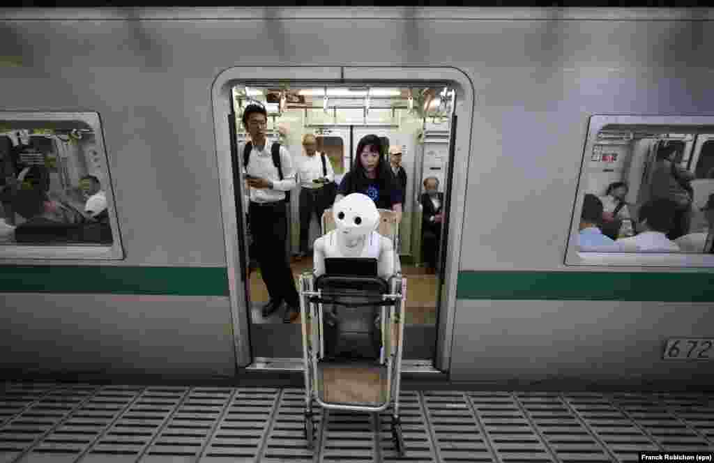 Tomomi Ota pulls a cart loaded with her humanoid robot Pepper as she boards a subway train in Tokyo, Japan.