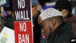 FILE - Abdirahman "OJ" Mohamed, of Seattle, holds a sign that reads "No Wall No Ban," during a protest against federal efforts to restrict immigration, Dec. 6, 2017, outside a federal courthouse in Seattle.