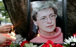 FILE - People light candles next to a portrait of Russian journalist Anna Politkovskaya during a rally in St. Petersburg in 2006.