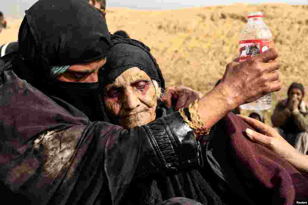 Displaced Iraqi women who just fled their home, rest in the desert as they wait to be transported while Iraqi forces battle with Islamic State militants in western Mosul.