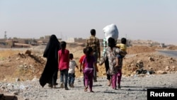 FILE - A displaced family from the minority Yazidi sect walks towards the entrance of Mosul, Aug. 21, 2014.