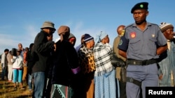 Un policier assure la sécurité près d’une file d’électeurs devant un bureau de vote dans le village de Magkhoakhoeng, près de Maseru, Lesotho, 2 février 2015.