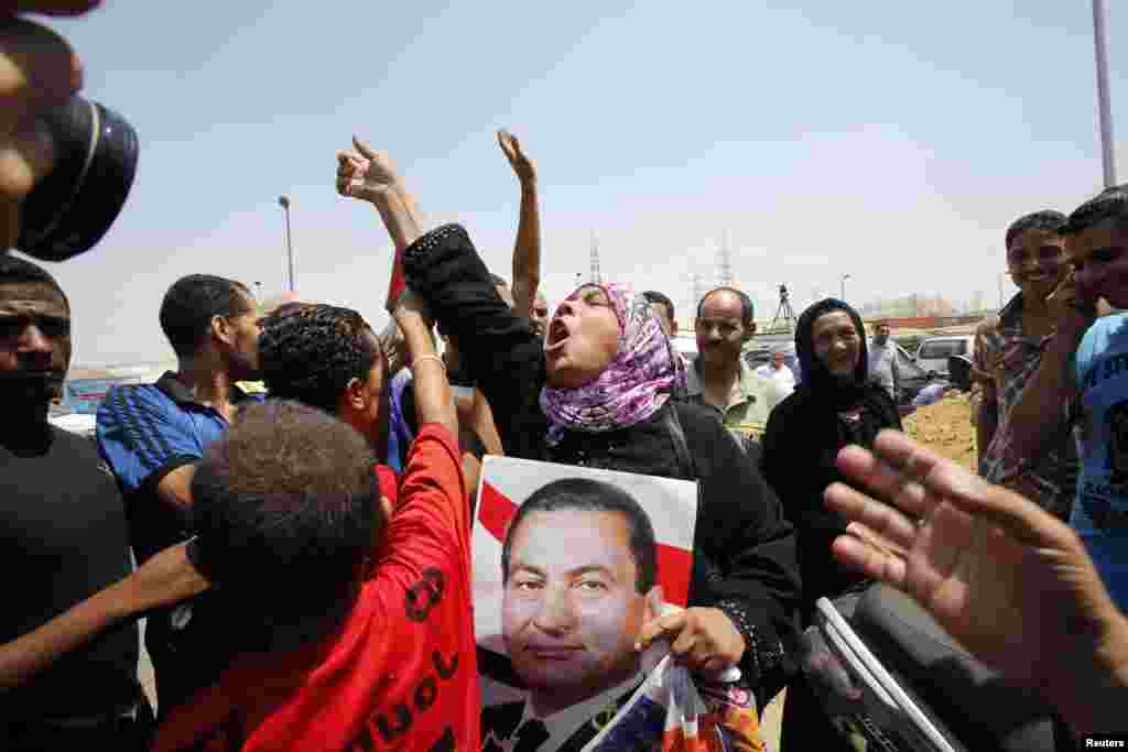 A supporter of former president Hosni Mubarak holds his poster to celebrate as she waits for his release in front of the main gate of Tora prison, Cairo, August 22, 2013.