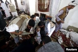 People help an injured man at the scene of a suicide bombing inside a mosque in Sana'a, March 20, 2015.