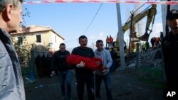 Seorang pria membopong tubuh seorang anak perempuan berusia lima tahun setelah gempa 6,4 magnitudo mengguncang Thumane, Albania barat, 26 November 2019. 