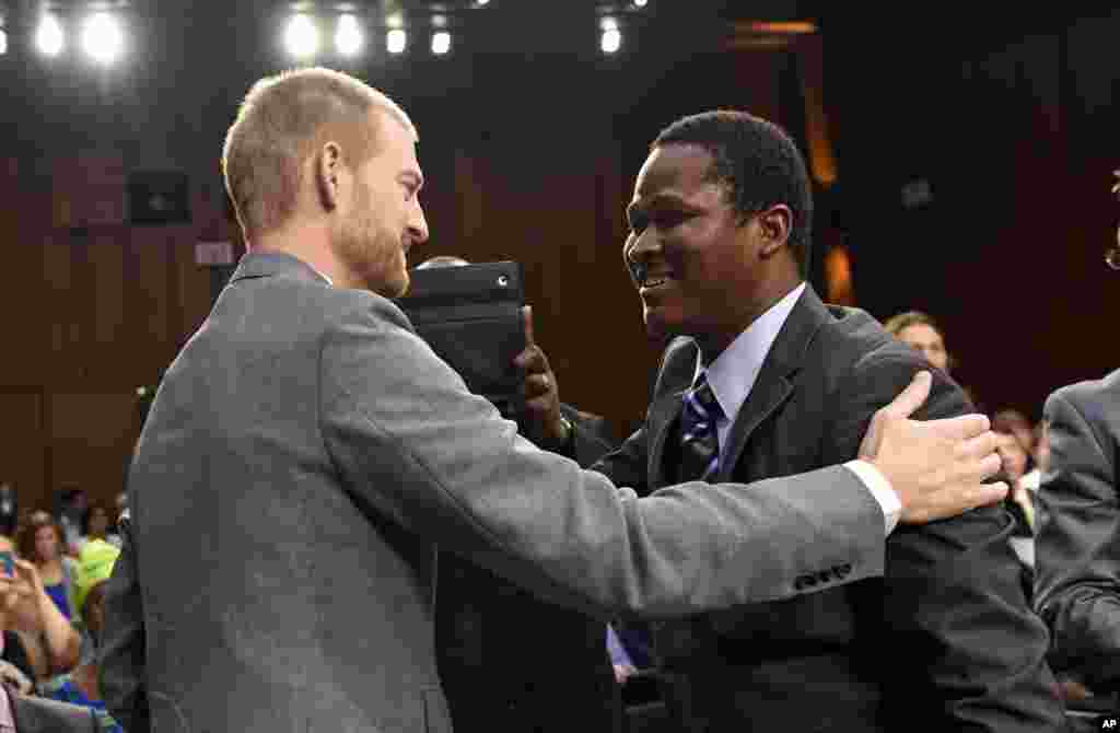 Ebola survivor Dr. Kent Brantly, left, former Medical Director of Samaritan's Purse Ebola Care Center in Monrovia, Liberia, talks with Ishmeal Alfred Charles, right, an aid worker from Sierra Leone, as they arrive to testify on Capitol Hill, Sept. 16, 2014.