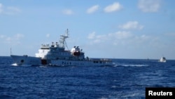 FILE - Chinese ships chase Vietnamese vessels, not shown, after they came within 10 nautical miles of a Chinese oil rig in the South China Sea, July 15, 2014. 