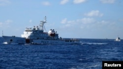 FILE - Chinese ships chase Vietnamese vessels, not shown, after they came within 10 nautical miles of a Chinese oil rig in the South China Sea, July 15, 2014. 