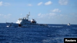 FILE - Chinese ships chase Vietnamese vessels, not shown, after they came within 10 nautical miles of a Chinese oil rig in the South China Sea, July 15, 2014. China has said that the sea holds 130 billion barrels of oil.