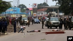 The bodies of people killed during election protests lie in the street, as Congolese troops stand near by in Kinshasa, Democratic Republic of Congo, Sept. 19, 2016.