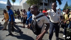 A demonstrator who began to break car windows, is detained by police during a protest against the proposed wage increase garment workers say is too little, at an industrial park in Port-au-Prince, Haiti, Dec. 11, 2013. 