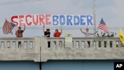 FILE - Demonstrators with signs on an overpass in Indianapolis, Indiana, protest against people who immigrate illegally July 18, 2014.