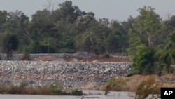 FILE - In this June 20, 2016 photo, a fishing boat passes near a construction site of the Don Sahong dam, near Cambodia-Laos borders, in Preah Romkel village, Stung Treng province, northeast of Phnom Penh, Cambodia.