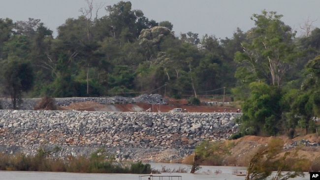 FILE - In this June 20, 2016 file photo, a fishing boat passes near a construction site of the Don Sahong dam, near Cambodia-Laos borders, in Preah Romkel village, Stung Treng province, northeast of Phnom Penh, Cambodia. The Mekong River Commission, an organization that groups together Laos, Cambodia, Vietnam and Thailand for joint management of the river, said in a statement it has received notice from Laos that it will undertake a process of consultation about the Pak Beng dam. (AP Photo/Heng Sinith, File)