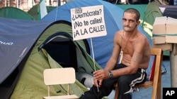 A demonstrator holding a sign camps out at Madrid's Puerta del Sol Square, May 29, 2011. The sign reads "Democrat? Don't be silent! To the streets."