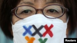 Učesnica protesta protiv posete predsednika Međunarodnog olimpijskog komiteta Tomasa Baha Hirošimi, u Tokiju, Japan, nosi masku koja sa precrtanim poljima umesto olimpijskim krugovima.