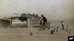 A man and two boys fight strong winds and blinding dust outside a shack in Oklahoma during the Dust Bowl of the 1930s, which blew away whole fields of topsoil.