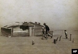 A man and two boys bend to the howling wind outside a ramshackle shack in Oklahoma during the Dust Bowl of the 1930s, which blew away whole fields of topsoil.