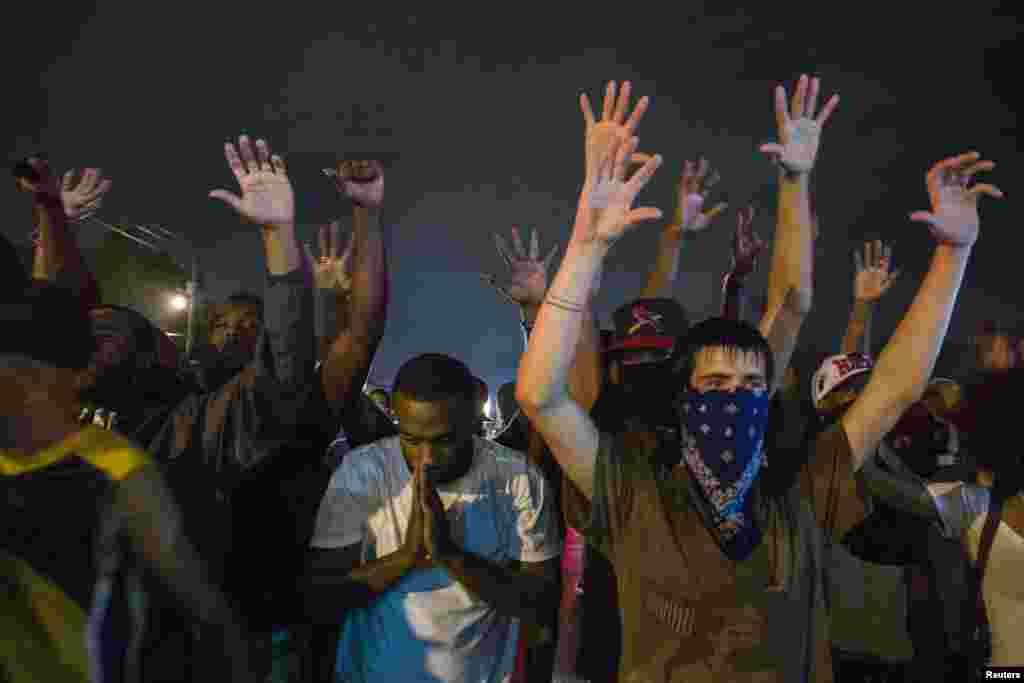Protesters gesture as they stand in a street in defiance of a midnight curfew in Ferguson, Missouri, Aug. 17, 2014.